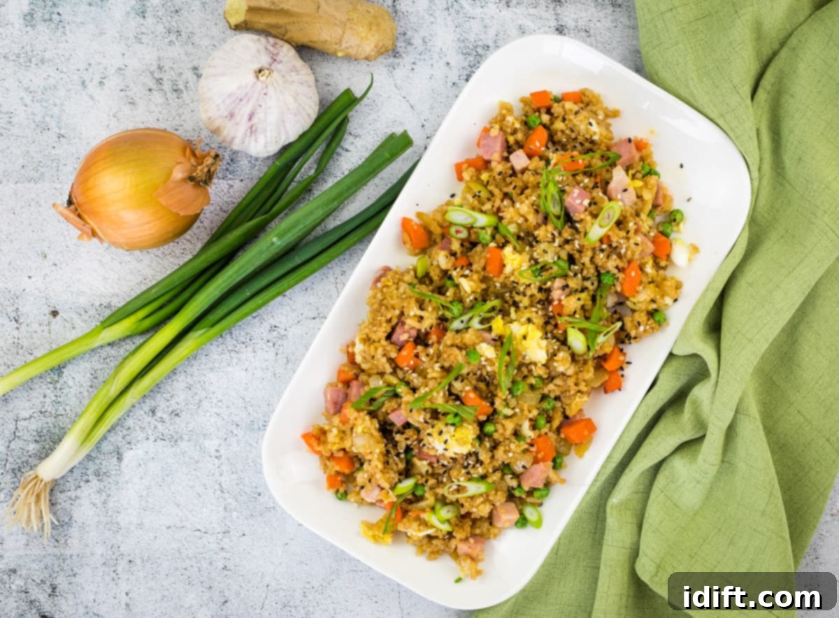 Ham fried rice on a white plate, garnished with green onions and a fried egg.