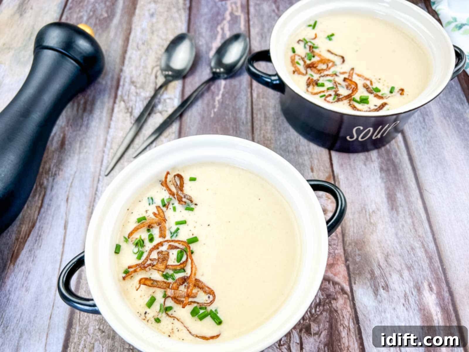 Two bowls of cream onion soup on a wooden table.