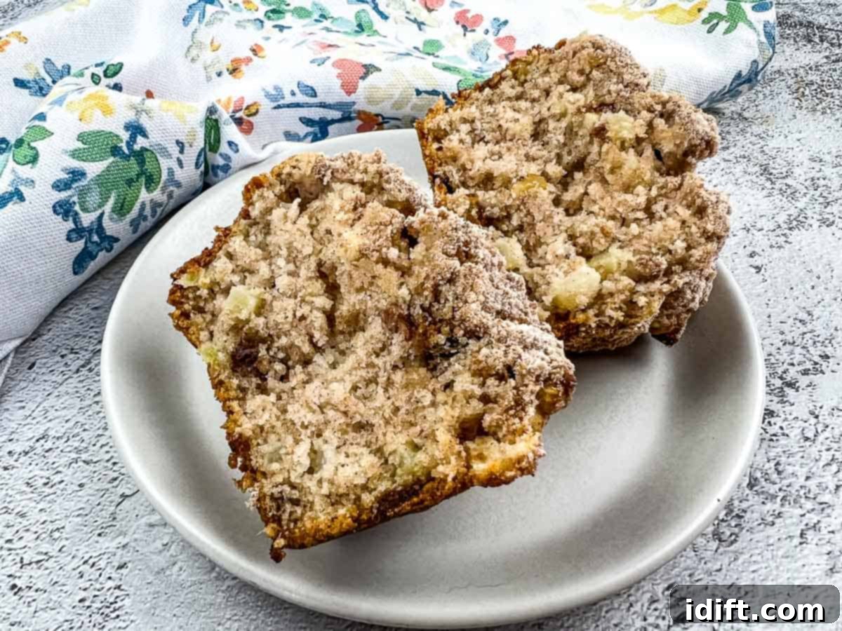 A delicious Apple, Date, and Walnut Muffin, cut in half to show its moist, fruity interior.