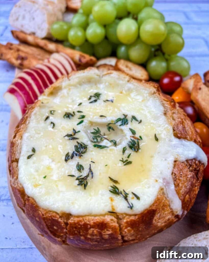 A bowl filled with cheese, grapes and bread.