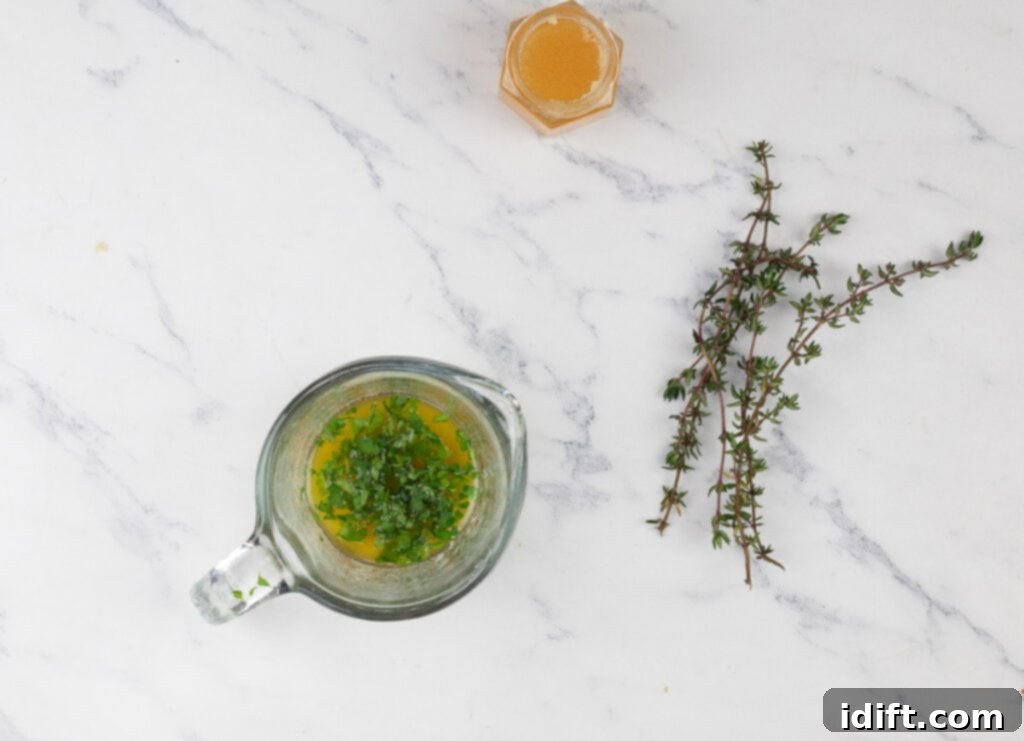 A bowl of honey and thyme on a marble table.