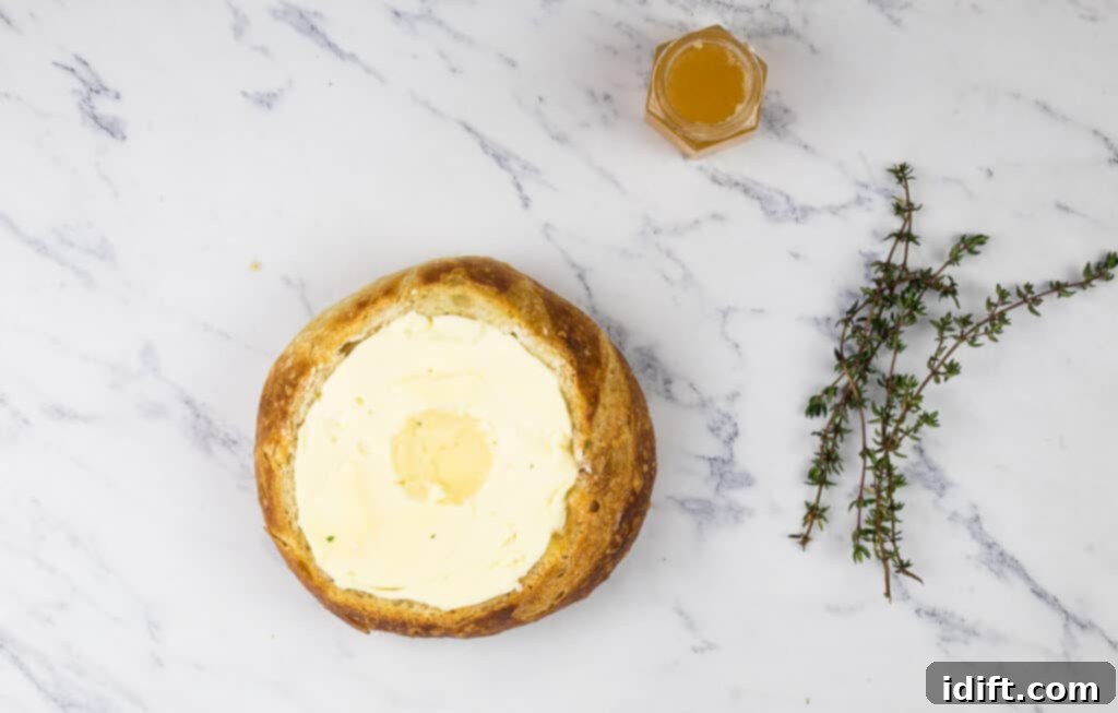 A loaf of bread with butter and a sprig of thyme.