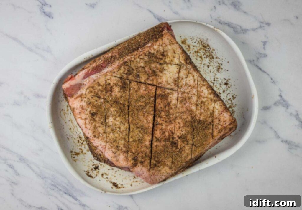 Succulent Traeger Smoked New York Strip Roast 8 A piece of New York strip roast on a white plate, completely covered with the dark coffee rub.