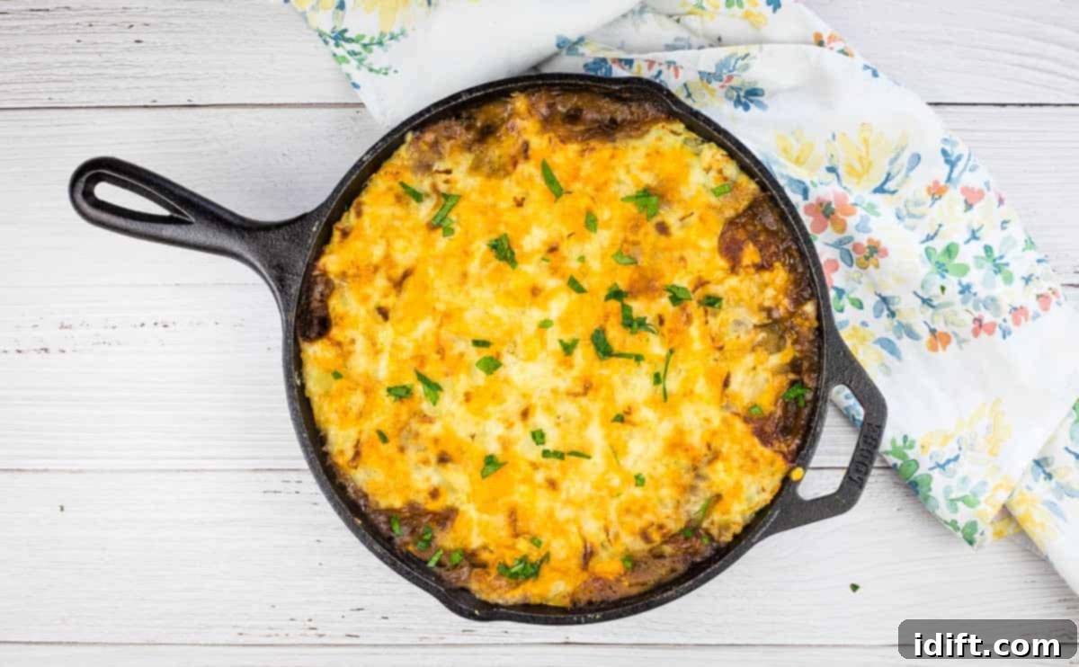 Hearty Leftover Roast Beef Shepherd's Pie in a cast iron dish, topped with mashed potatoes and herbs.
