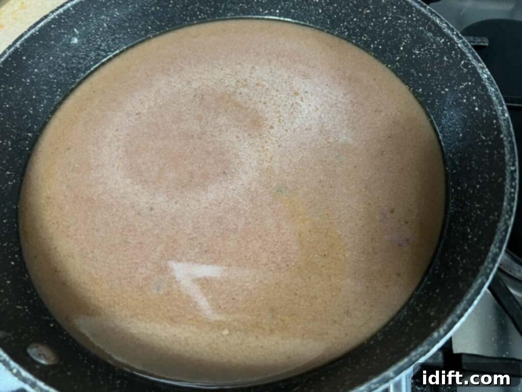 Rich, simmering gravy in a frying pan, thickening to a perfect consistency, ready to be poured over the roast.