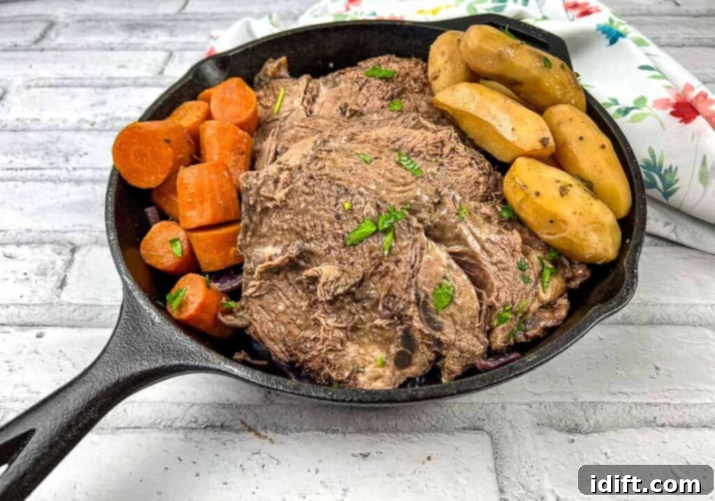 A cast iron skillet filled with a finished German Pot Roast, showcasing tender beef, carrots, and potatoes in a rich gravy.