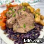 Roast beef with red cabbage and potatoes on a white plate.