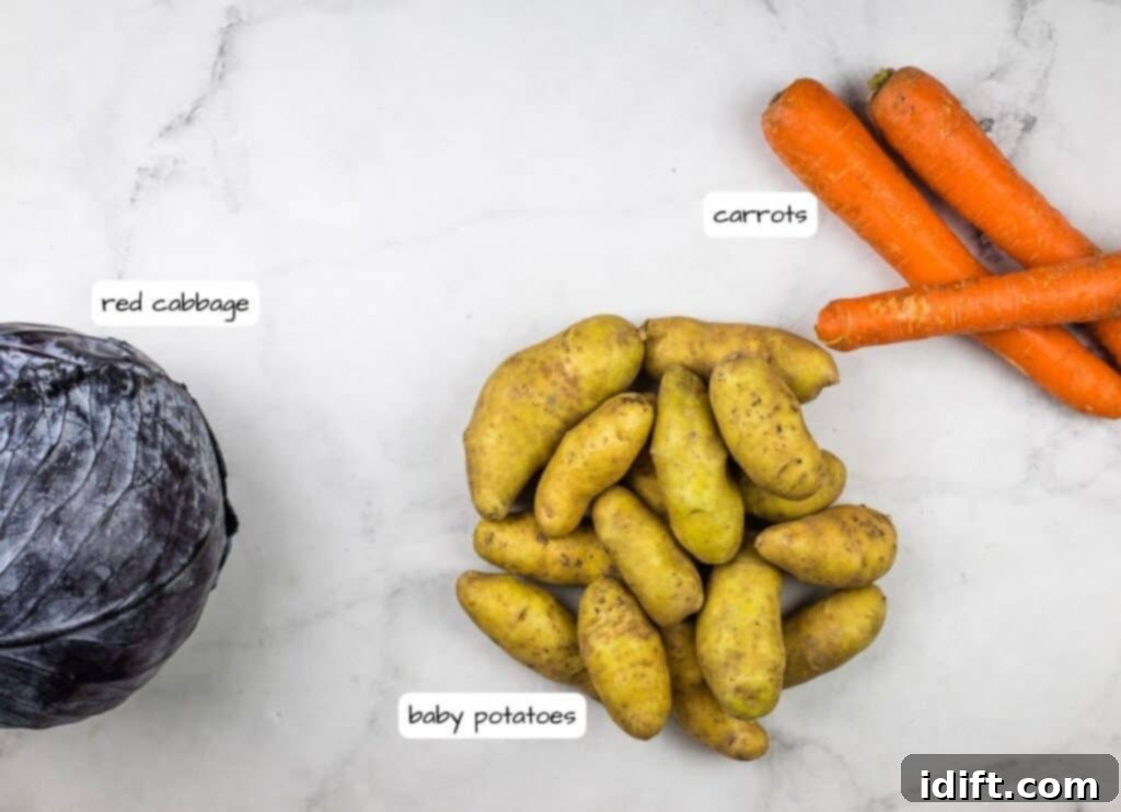 Freshly prepared vegetables for German Pot Roast: cut carrots, sliced red cabbage, and baby potatoes on a marble countertop.