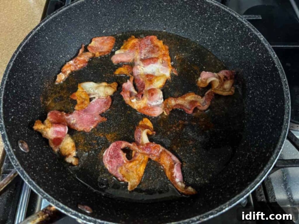 Crispy bacon sizzling in a frying pan on a stove, creating the flavorful base for the pot roast.