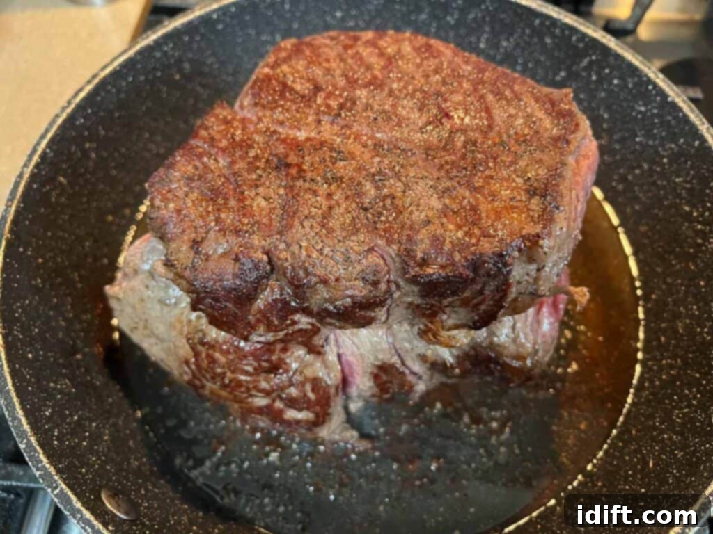 Close-up of a pot roast developing a perfect, caramelized crust in a hot frying pan, adding deep flavor.