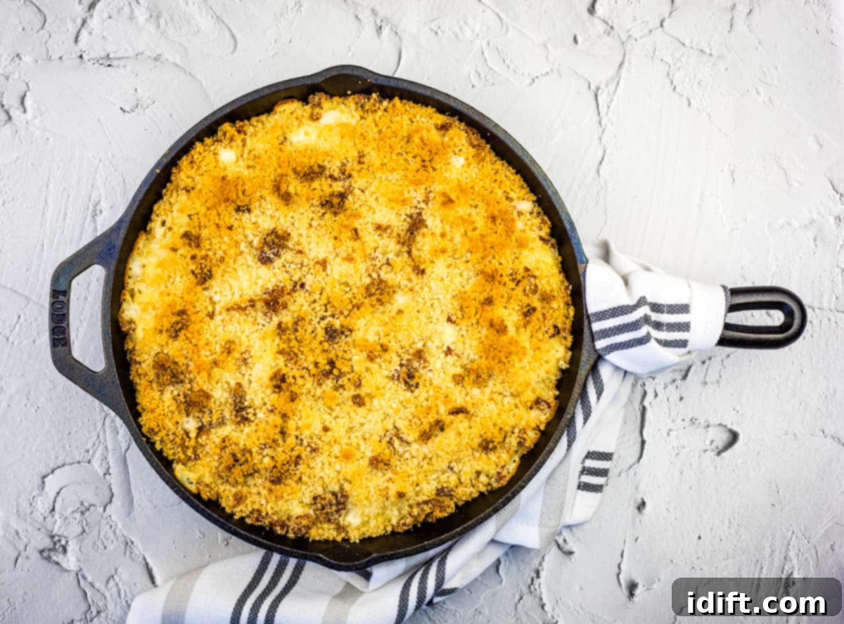 A rustic cast-iron skillet brimming with creamy, golden Smoked Mac & Cheese, topped with a crispy, savory crust.