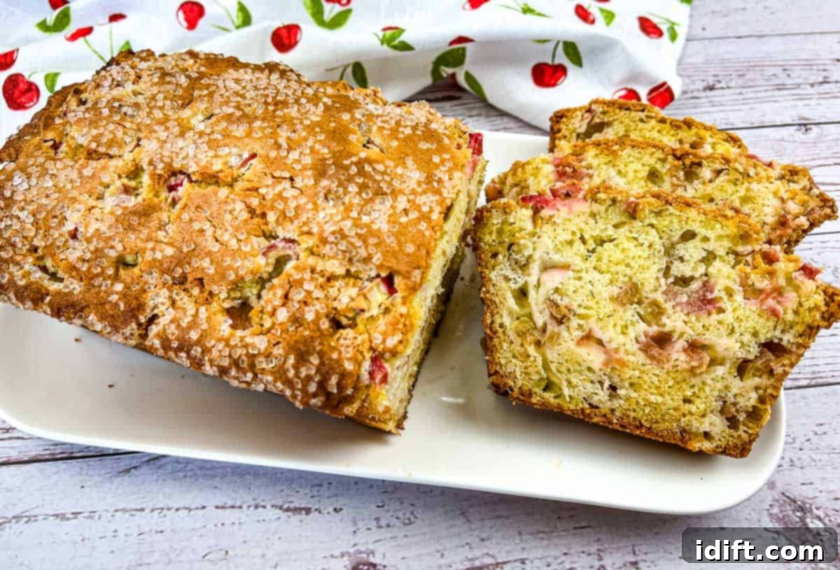 Timeless Comfort: Grandma's Kitchen Favorites 4 A whole loaf of Rhubarb Bread with a few cut slices on a white plate, ready to serve.
