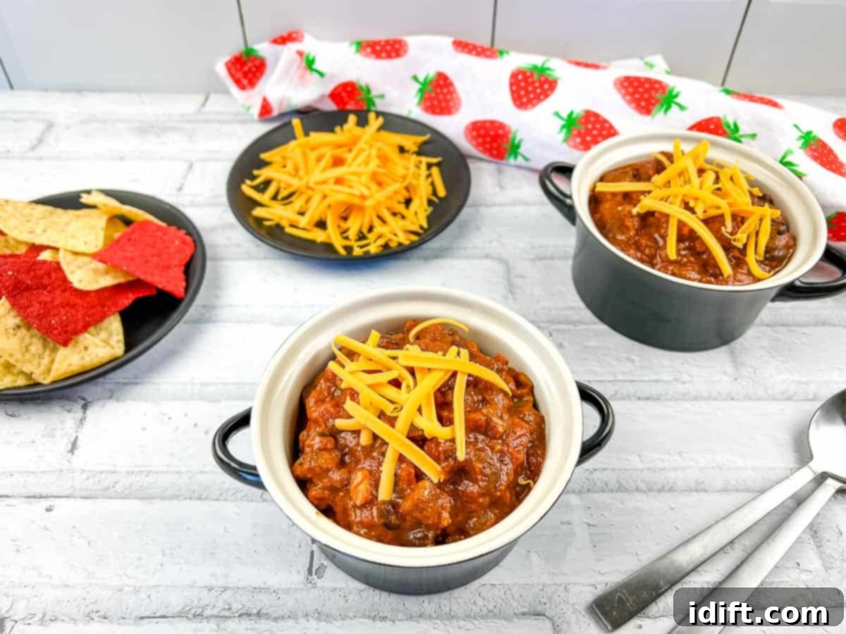 Two bowls of smoked brisket chili, tomatoes, and bread.