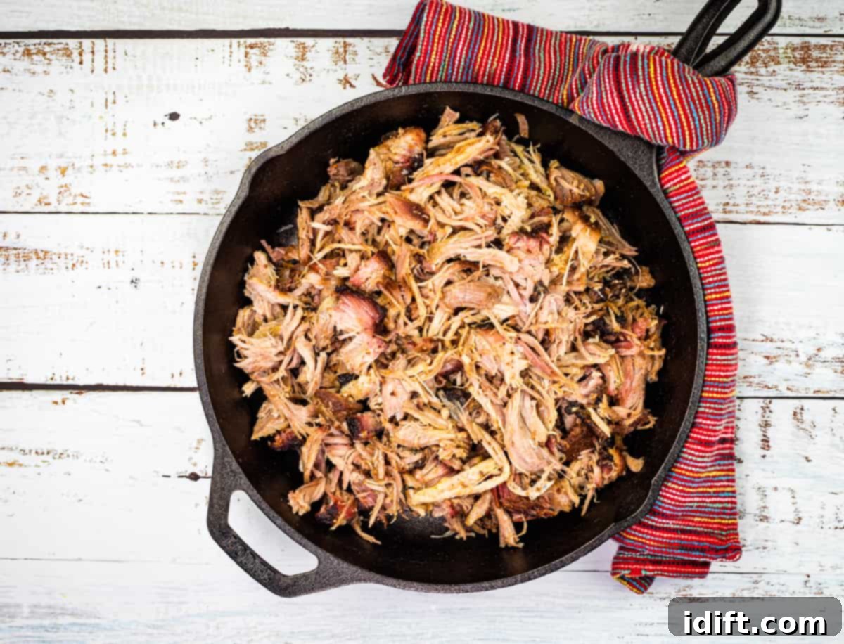 Two cast iron skillets with smoked pulled pork in them.