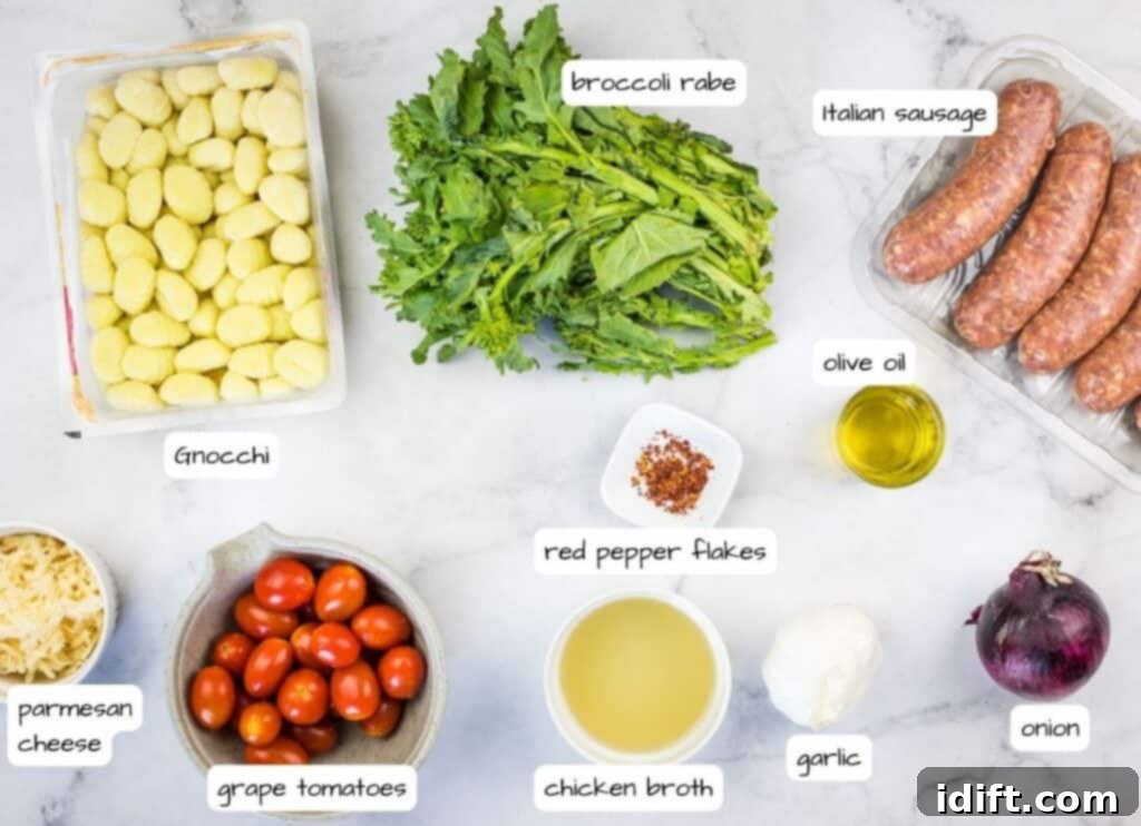 A collection of fresh ingredients for Skillet Gnocchi with Sausage and Broccoli Rabe, including sausage, broccoli rabe, tomatoes, onions, and gnocchi, neatly arranged on a marble countertop.