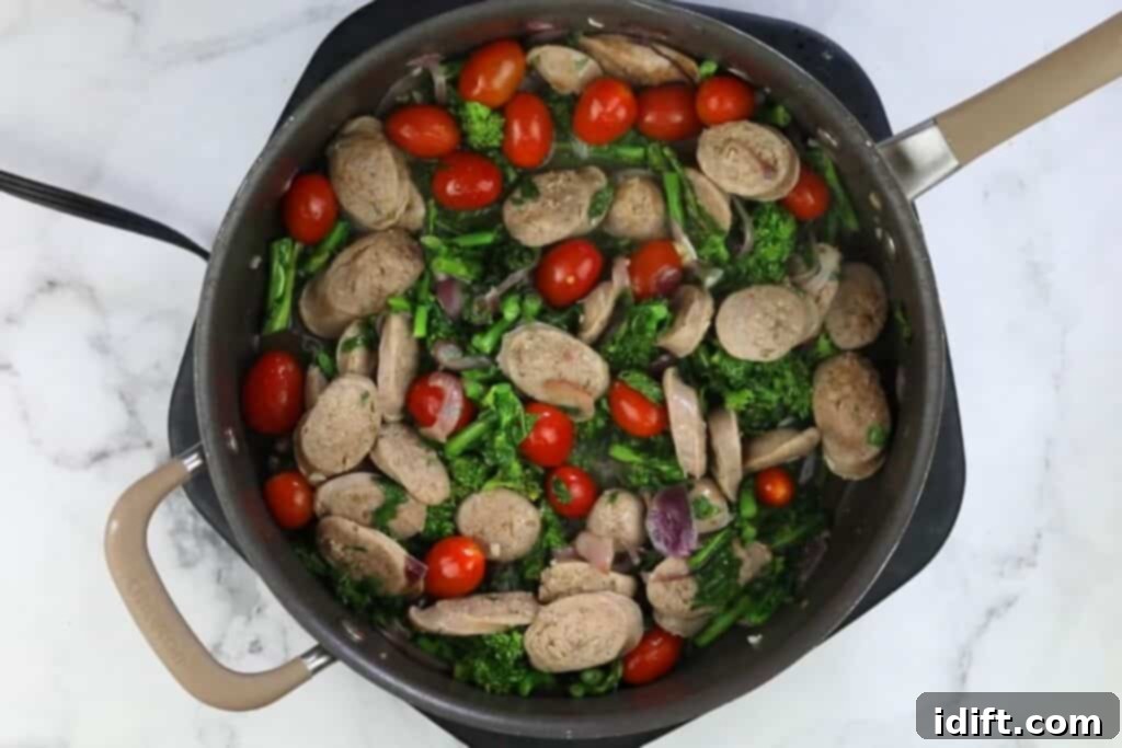 Sweet grape tomatoes added to the simmering skillet with sausage and broccoli rabe, ready to burst with flavor.