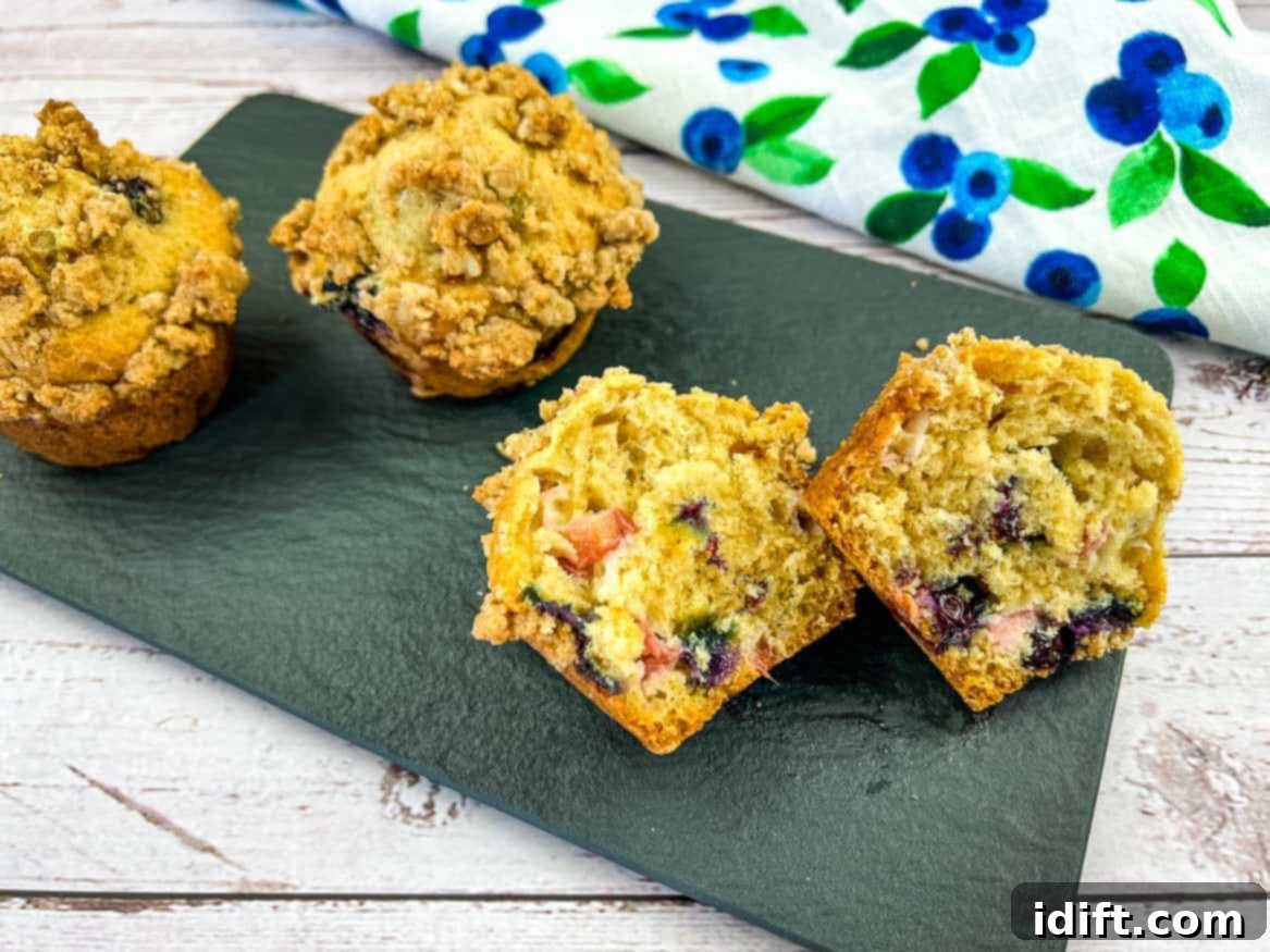 Blueberry Rhubarb Muffins on a black plate with one muffin cut in half.