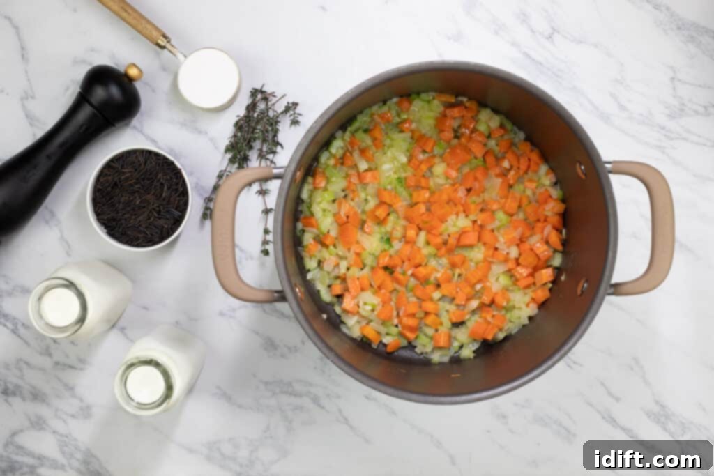 Rich Chicken and Wild Rice Soup 6 Close-up of soup ingredients (carrots, celery, onions) being sautéed in a pot.