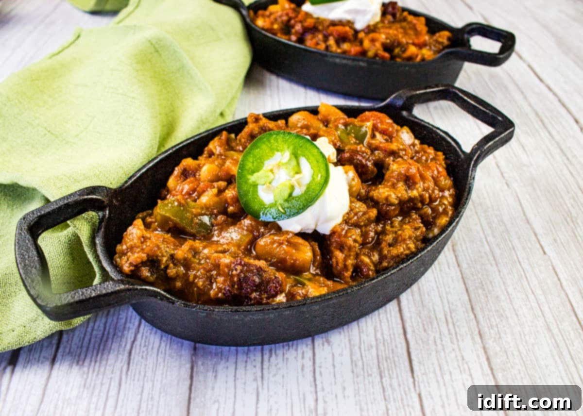 A robust black cast iron bowl brimming with hearty Over the Top Chili, steam rising, ready to be enjoyed.