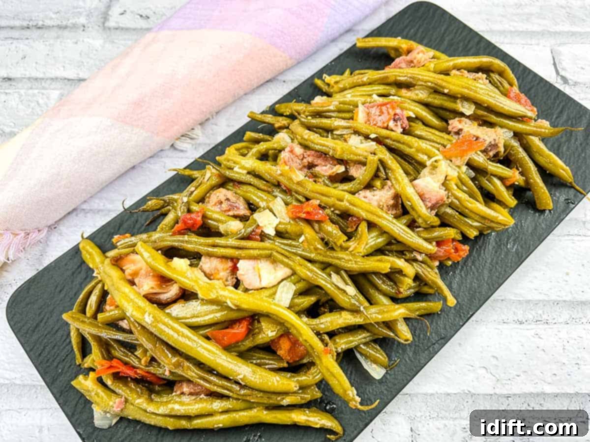 Green beans with pork on a black plate.