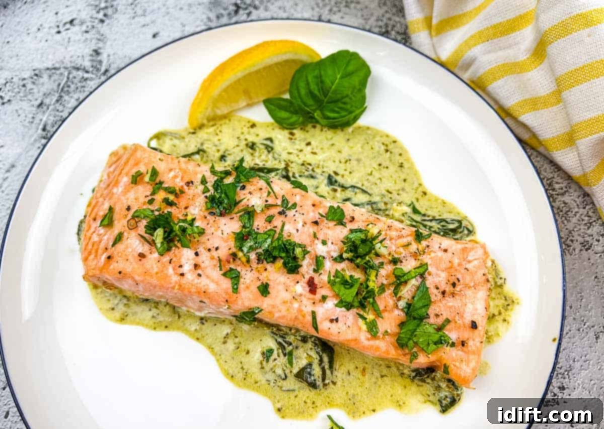 Low-Carb Dishes That Delight, Not Overwhelm 10 Perfectly baked salmon fillets with a vibrant green pesto sauce and fresh spinach, served on a white plate.
