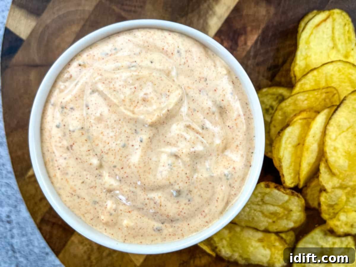 A person dipping a pretzel into a bowl of cajun dip.