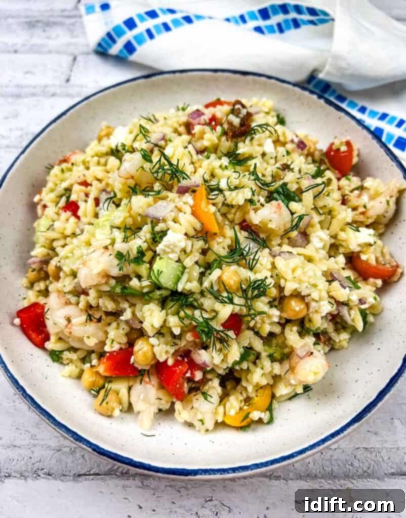 A plate of Mediterranean Orzo Salad with shrimp and vegetables, beautifully garnished and ready to be served.