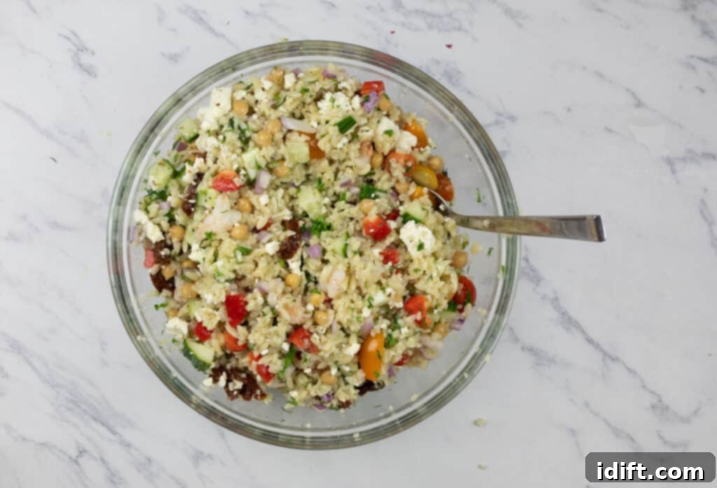 A close-up shot of a prepared Mediterranean Orzo Salad with Shrimp in a stylish glass bowl, glistening with dressing and ready to be served.