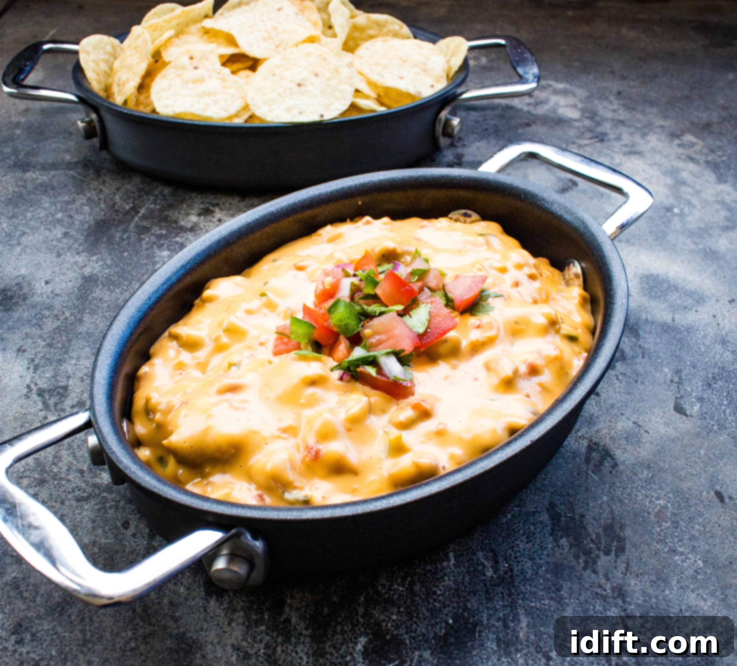 Smoked queso in a black pot, bubbling and ready for dipping with golden tortilla chips.