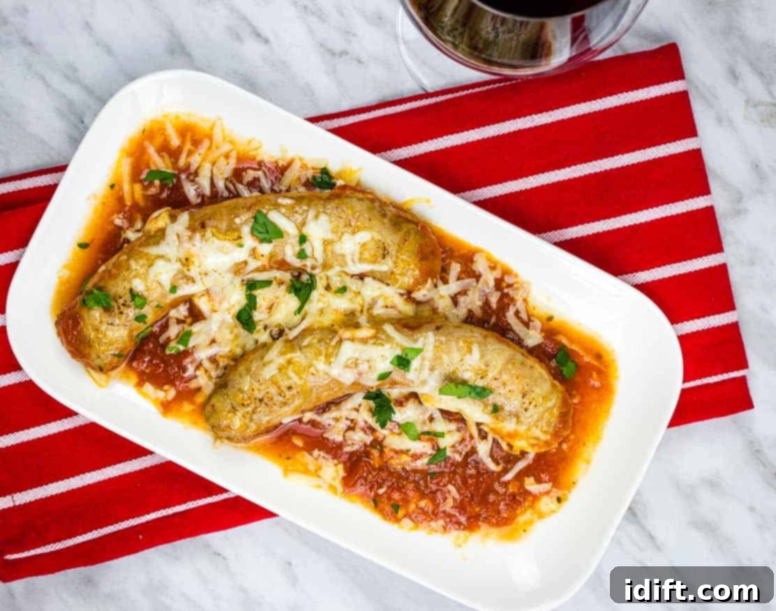 Sausage Parmigiana on a white plate with a red napkin and a glass of wine.