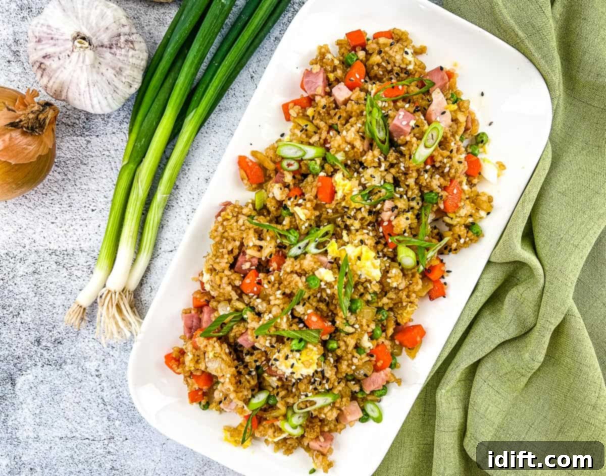 Hearty ham fried rice on a white plate, garnished with green onions.