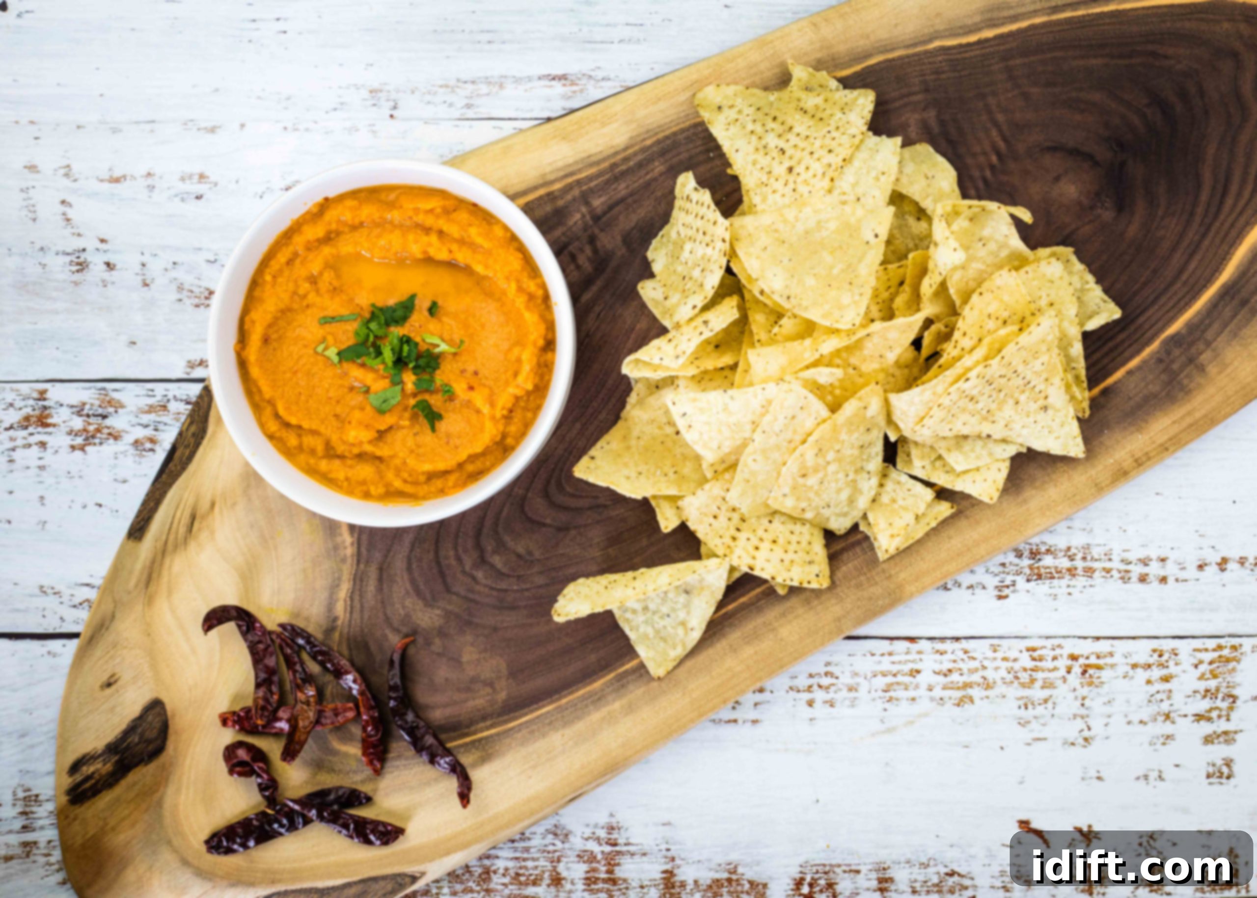 Authentic Chile de Arbol Salsa served in a bowl with tortilla chips and dried chilies on a wooden board.