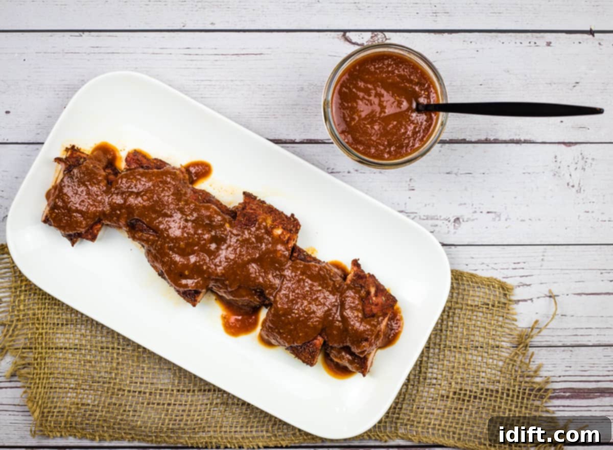 Succulent ribs generously coated with homemade Bourbon BBQ Sauce on a white plate, ready to be enjoyed.