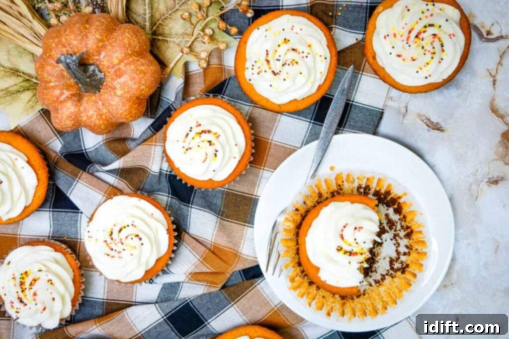A close-up of beautifully frosted Fall Brownie Cupcakes, decorated with autumnal sprinkles, resting on a rustic wooden surface.