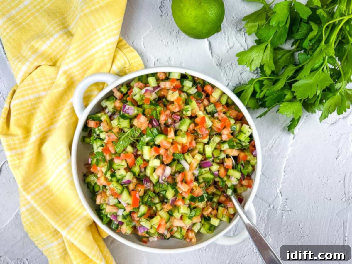 Fresh and vibrant Shirazi Salad in a white serving bowl, garnished with herbs.