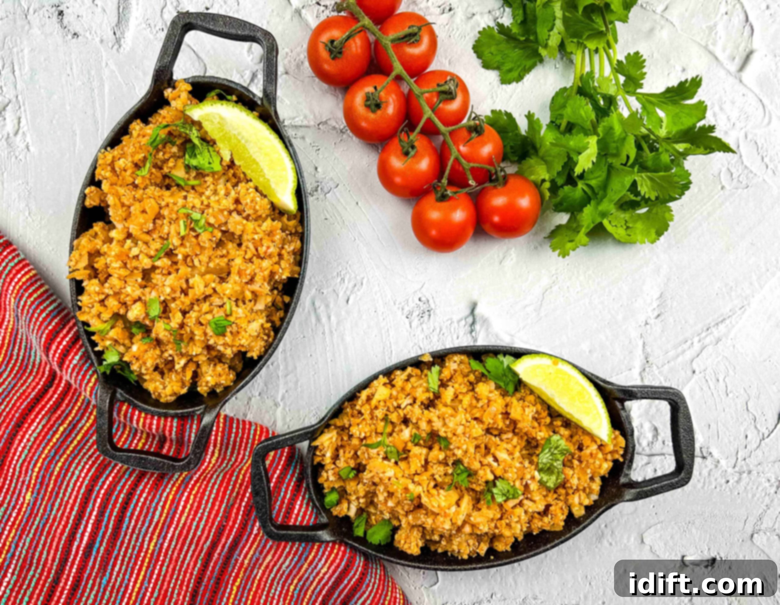 Close-up of vibrant Mexican Cauliflower Rice with tomatoes and cilantro in the background.