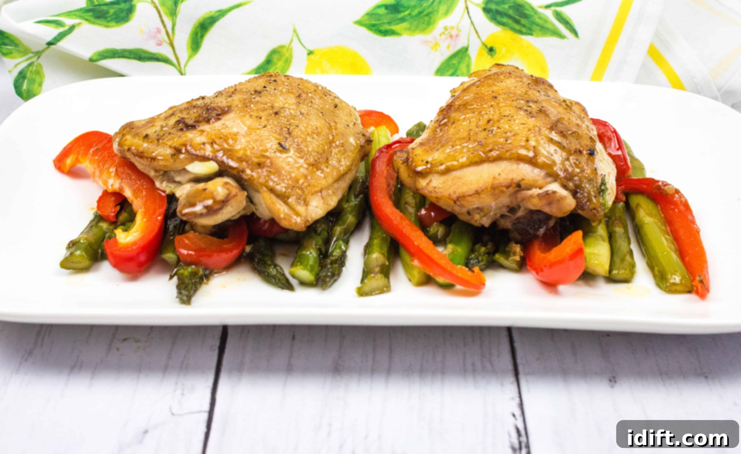Perfectly cooked Garlic Chicken Skillet with colorful bell peppers and asparagus, served on a white plate.
