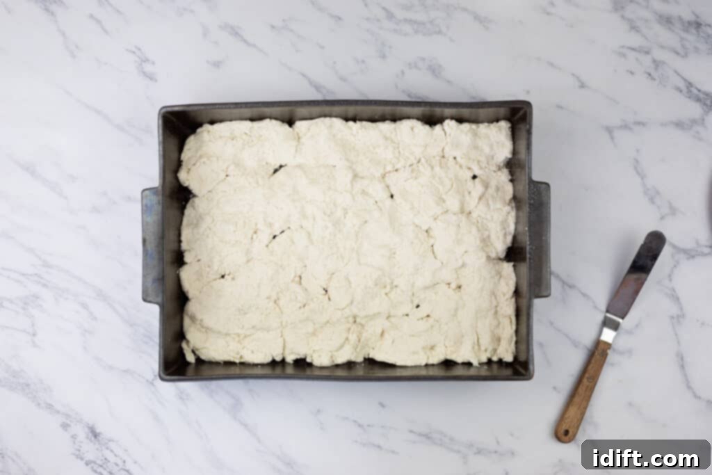 The Bisquick layer spread evenly into a greased baking dish with a spatula.