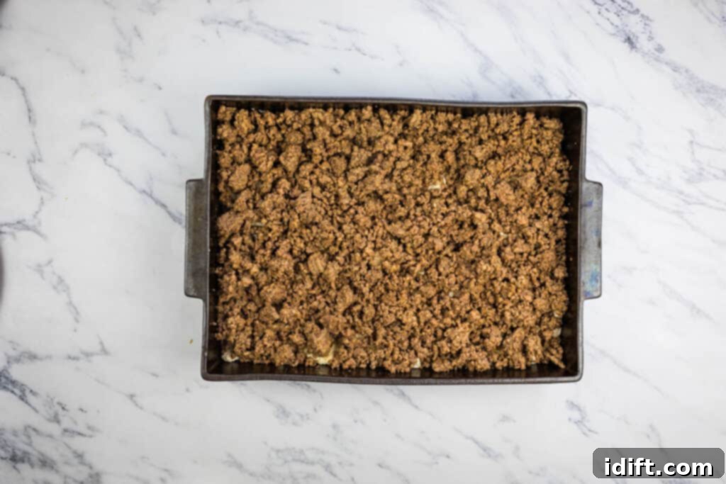 The seasoned ground beef mixture spread over the Bisquick base in a baking pan.