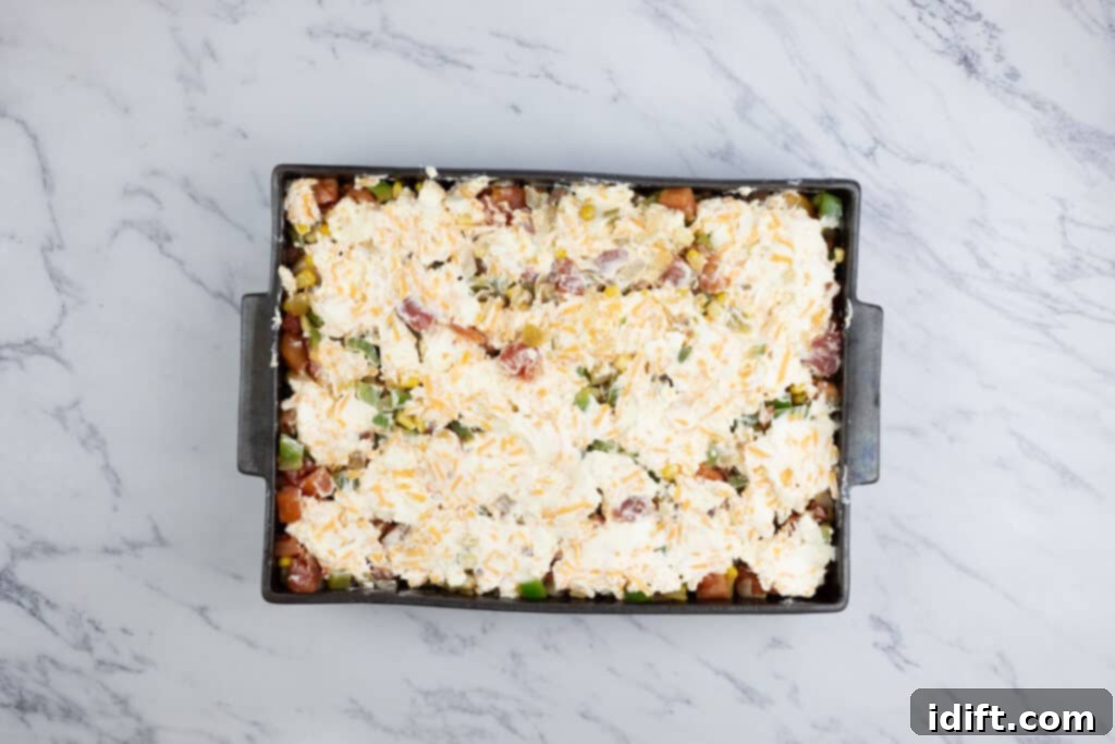 The creamy cheese mixture spread over the vegetable layer in the casserole dish.