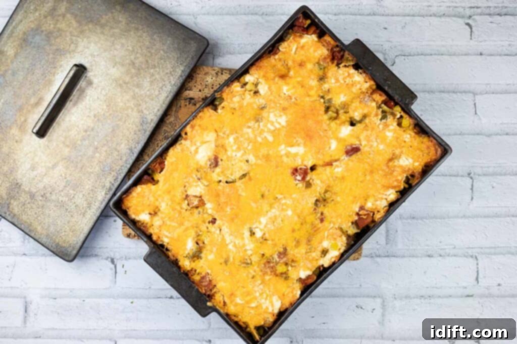 A slice of cheesy John Wayne casserole in a cast iron pan, ready to be served.