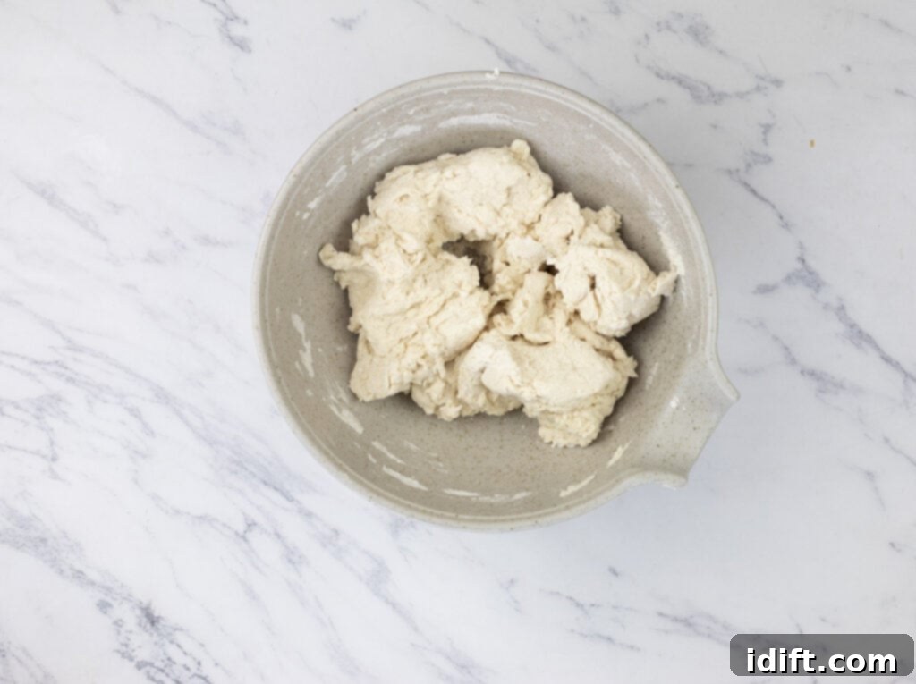 Bisquick dough mixture in a mixing bowl on a marble countertop.