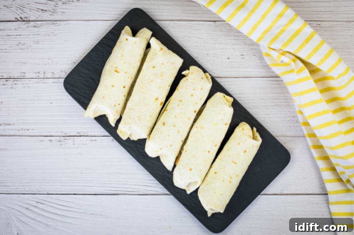 Several freezer breakfast burritos wrapped in plastic bags and placed on a rustic wooden table, ready for a grab-and-go meal.