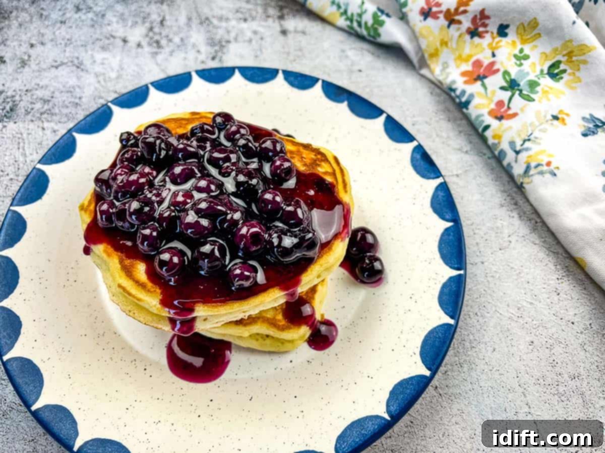 A plate featuring a stack of fluffy Buttermilk Pancakes generously topped with a vibrant Blueberry Sauce.