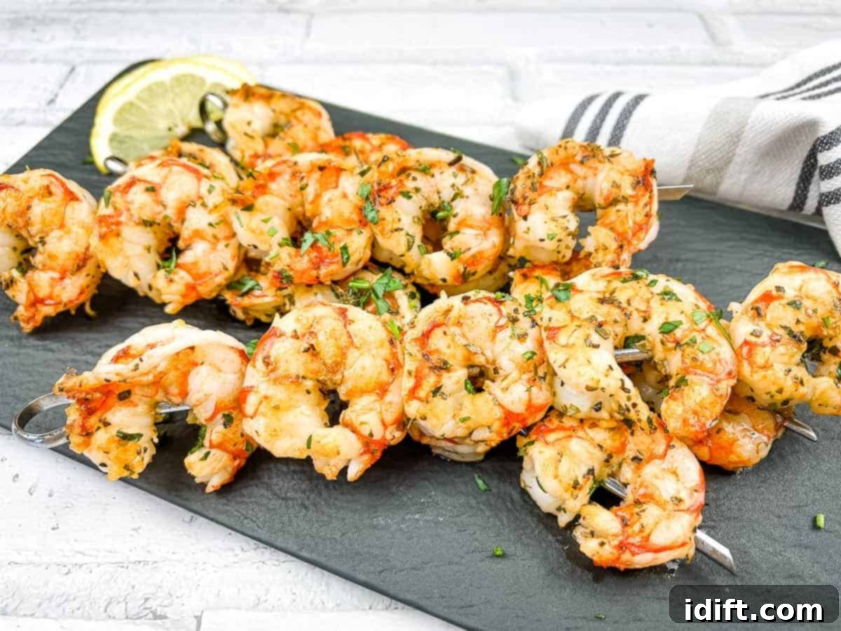Shrimp skewers on a white plate with lemon wedges.