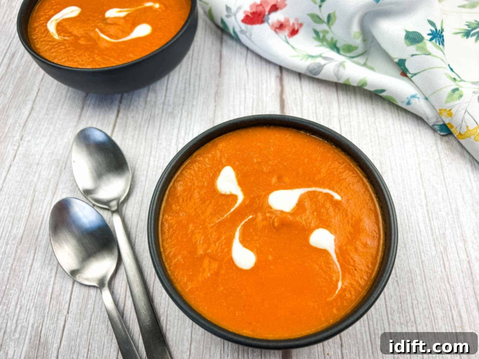 A bowl of oven-roasted tomato soup with two spoons.