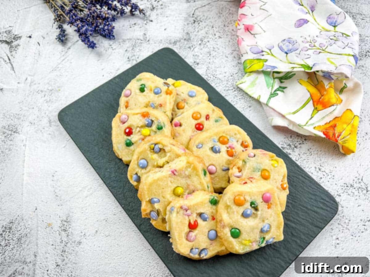 Colorful Shortbread M&M cookies arranged on a black plate, adorned with delicate flowers.