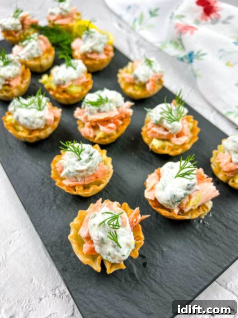 Smoked salmon tartlets with dill on a tray.