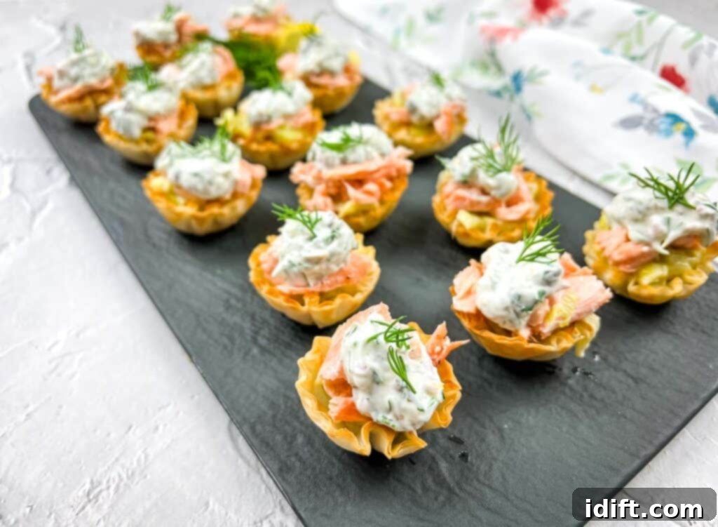 Smoked salmon tartlets with dill on a tray.