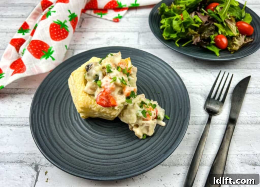 A black plate with a sandwich and salad on it.